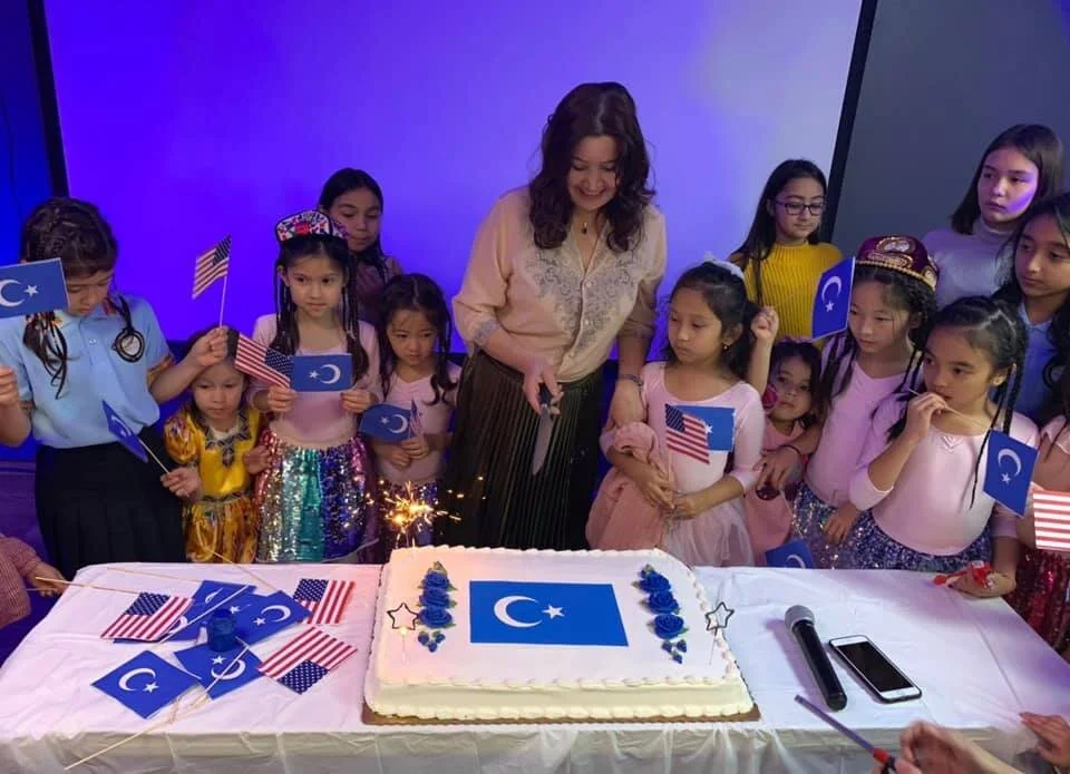 Students celebrating with a cake, Uyghur and American flags